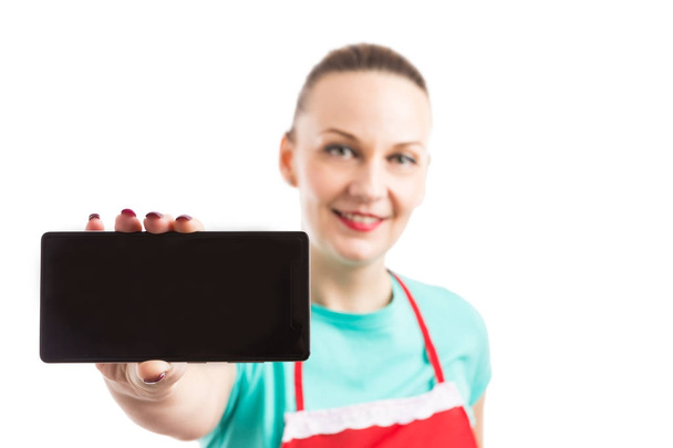 Mujer con delantal rojo mostrando teléfono inteligente o teléfono celular en blanco sc
 - Foto, Imagen