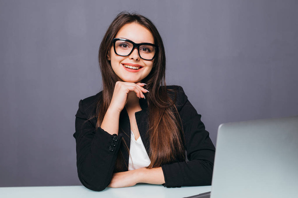 Portrait of a cheerful businesswoman sitting at the table in office and looking at camera - Foto, Imagem