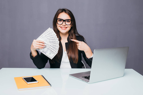 Портрет щасливої бізнес-леді з грошима в руках на робочому місці з ноутбуком
 - Фото, зображення