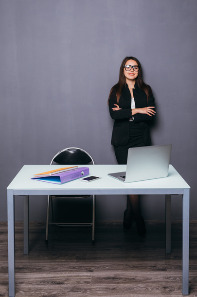 Усміхнена молода бізнес-леді стоїть біля офісного столу
 - Фото, зображення