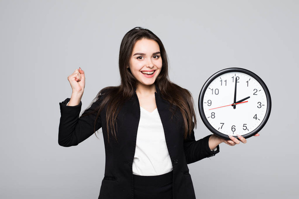 Happu excité femme d'affaires en costume qui tient horloge dans les mains fond gris isolé
 - Photo, image