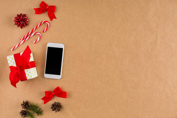 Phone and Christmas decorations on craft paper background, top view, flat lay. - Photo, Image