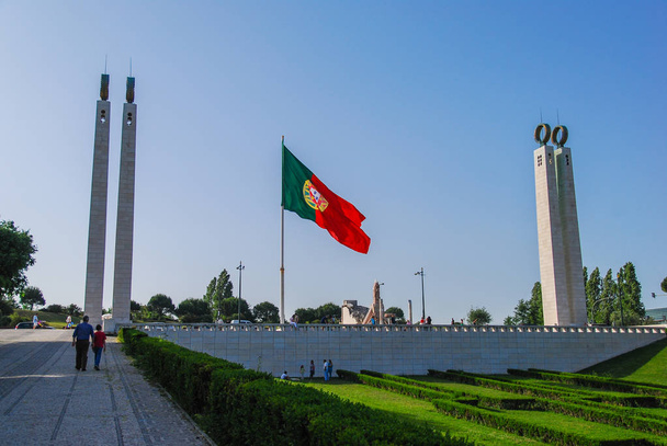 Bandera de Portugal en la plaza de Lisboa entre dos monumentos geométricos
 - Foto, imagen
