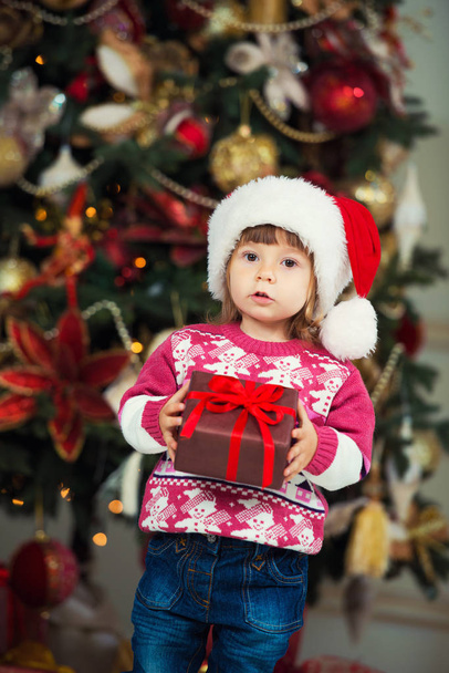 La muchacha feliz con el regalo en las manos sobre el fondo del árbol de Año Nuevo
. - Foto, imagen