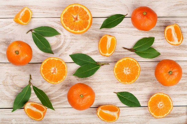 Orange oder Mandarine mit Blättern auf weißem Holzgrund. flache Lage, Draufsicht. Zusammensetzung der Früchte - Foto, Bild