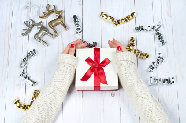 Woman holding Christmas gift on a wooden table background - Foto, Bild