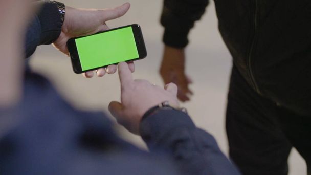 Mann zeigt seinem Freund neue App auf seinem Handy Telefon mit Greenscreen. Mann benutzt Telefon mit grünem Bildschirm - Foto, Bild