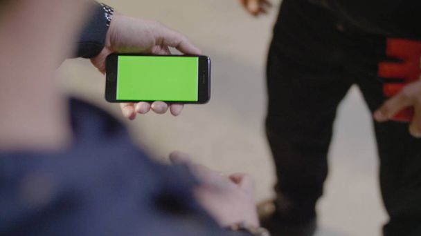 Homme montre à son ami nouvelle application sur son téléphone mobile. Téléphone avec écran vert. L'homme utilise un téléphone avec un écran vert
 - Photo, image