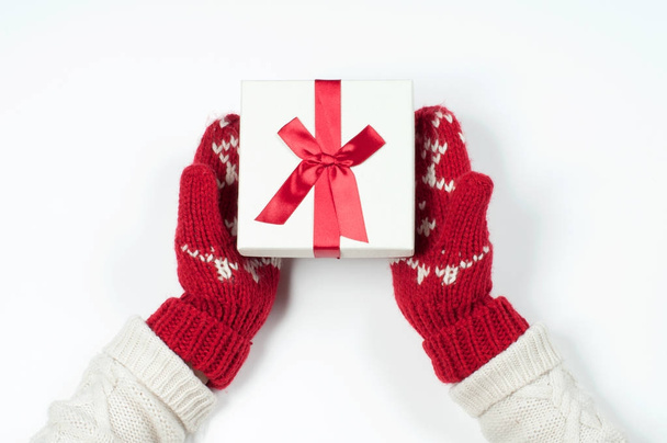Female hands holding christmas gift in red mittens - Foto, imagen