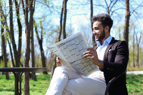 Mulatto guy reading newspaper in caf and smiles. - Zdjęcie, obraz