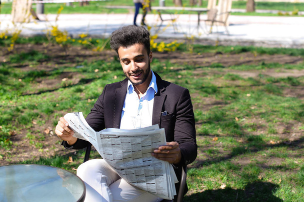 Арабский только что купил новую ежедневную газету и чтение в парке
. - Фото, изображение