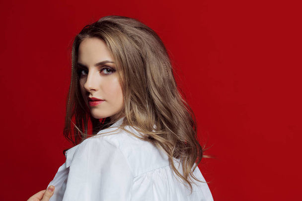 Stylish young woman in white. Red background - Φωτογραφία, εικόνα