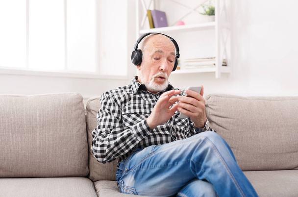 Senior man listening to music with headphones - Fotó, kép
