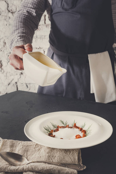 Camarero vertiendo caldo a la sopa de crema de champiñones
 - Foto, Imagen