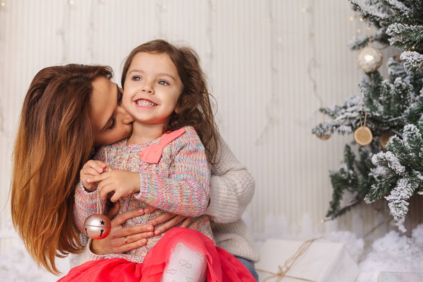 クリスマスイブに彼女の娘と一緒に楽しんで若いママ - 写真・画像