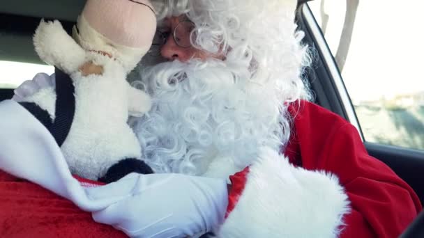 Happy Santa Claus playing with toys in car - Footage, Video