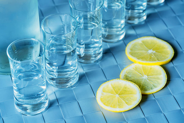 Vodka shot glass and lemon on blue surface - Photo, Image
