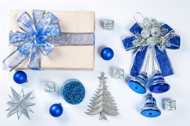 Klassz karácsonyi ajándék doboz kék játékok és új évet dekorációt fehér barna papír mutatja be. Boldog karácsonyi kártya háttér - Fotó, kép