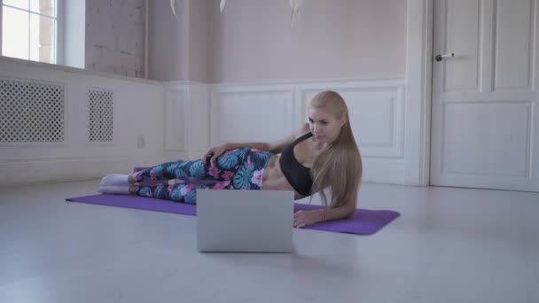 ホーム フィットネス。若い女性のことをトレーニングします。筋肉や関節をストレッチします。ノート パソコンでインターネット上の動画を見てください。 - 映像、動画