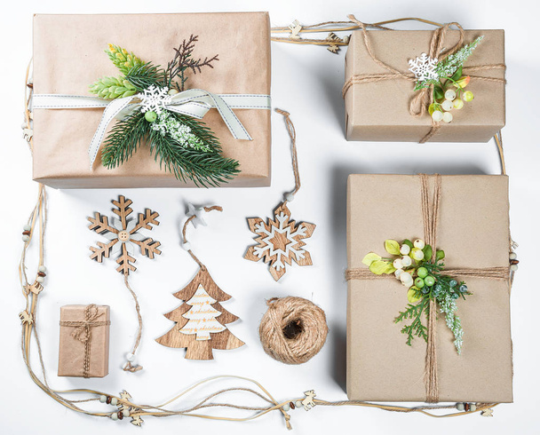 Шикарные рождественские подарки коробка подарки в коричневой бумаге с игрушками и новогодний декор на белом. Весёлого рождественского фона
 - Фото, изображение