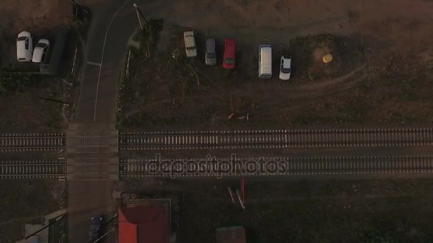 Luftaufnahme einer Kreuzung aus einer Asphaltstraße und einer zweispurigen Eisenbahn - Filmmaterial, Video