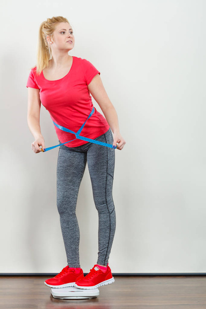 Woman wearing sportswear standing on weight machine - Foto, afbeelding
