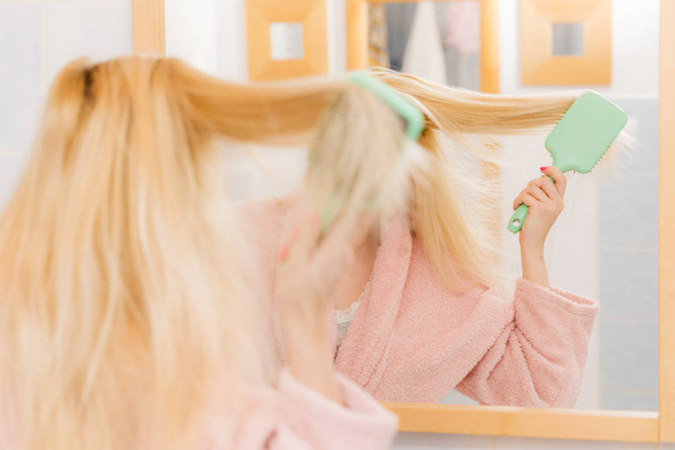 Woman wearing dressing gown brushing her hair - Foto, afbeelding