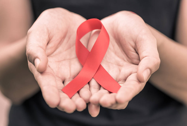 Руки женщины держат красную ленту для информирования о СПИДе
.  - Фото, изображение