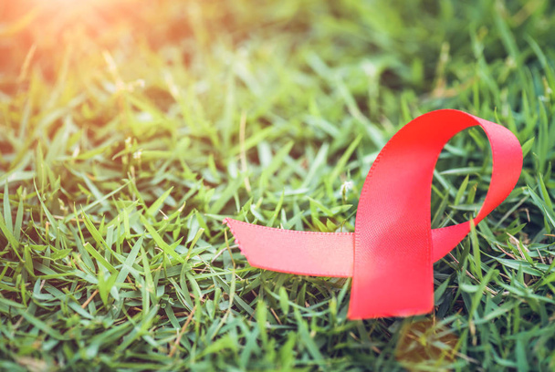 Rood lint bewustzijn op groen gras achtergrond voor Wereld Aids Dag campagne. - Foto, afbeelding