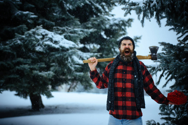 Christmas hipster lumberjack with ax in wood. s - 写真・画像