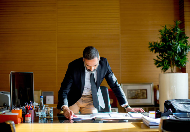 Komea keski-ikäinen liikemies modernissa toimistossa
 - Valokuva, kuva