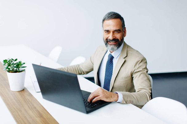 Przystojny biznesmen średnim wieku działa na laptopie w biurze - Zdjęcie, obraz