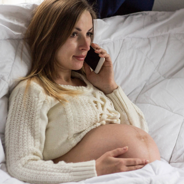 Pregnant girl talking on phone, chatting with her best friend ab - Photo, Image