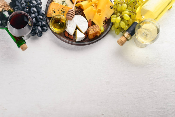 Food background with cheese. Blocks of moldy cheese, grapes, honey, nuts over on white background. Copy space. Top view. - Photo, image