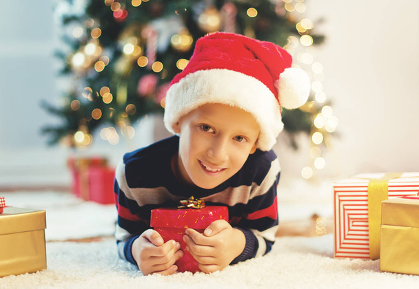 Cute little boy with present on Christmas eve thinking  - Фото, зображення