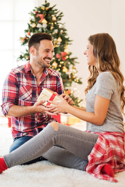 若い夫婦とクリスマスの朝にプレゼントを愛する - 写真・画像