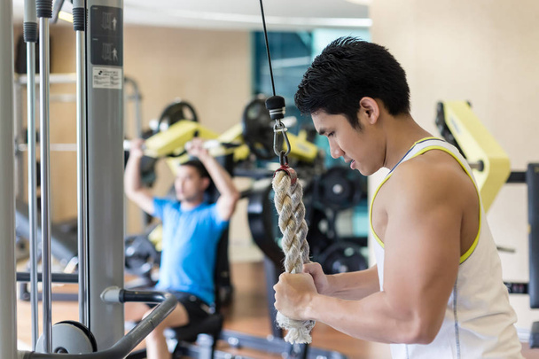 Strong young man exercising triceps pushdown at the rope cable m - Photo, Image
