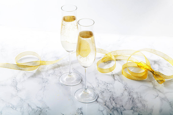 Two flute glasses with champagne on marble background. Direct light with heavy shadows.  - Photo, Image
