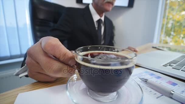 Businessman drinks coffe while watching the laptop screen - Metraje, vídeo