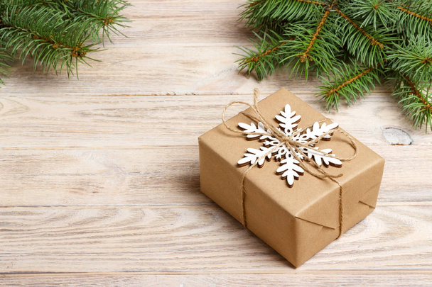 Joulun käsintehty lahjapakkaus koristeltu käsityöpaperilla ja valkoisella lumihiutaleella valkoisella puupohjalla. Talvi xmas loma teema kuusen oksat Uusi vuosi
 - Valokuva, kuva