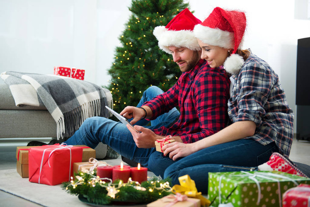 Young couple with Santa Claus hats shopping online Christmas gif - Фото, зображення