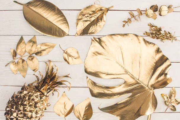 vista superior del conjunto de varias hojas doradas y piña en la superficie de madera
 - Foto, Imagen
