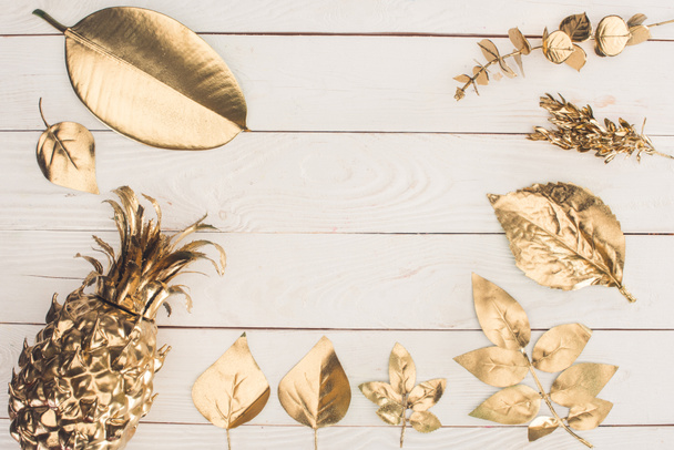 vista dall'alto di serie di varie foglie d'oro e ananas su superficie di legno
 - Foto, immagini