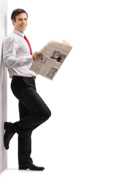man with a newspaper leaning against a wall - Zdjęcie, obraz