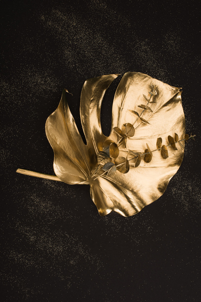 close up view of big golden leaf and plants on black surface - Zdjęcie, obraz
