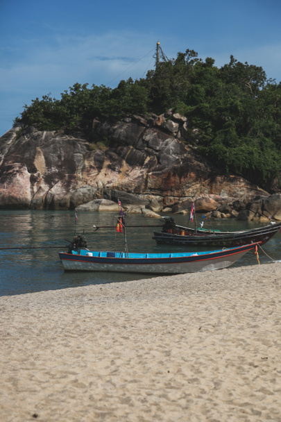 kivinen rannikko lähellä hiekkarantaa vanha vene aurinkoisena päivänä
 - Valokuva, kuva