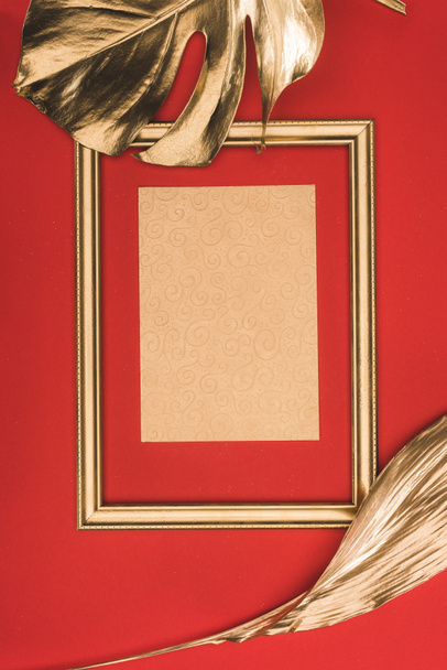 vista superior del marco de fotos dorado, hojas y papel en blanco aislado en rojo
 - Foto, imagen