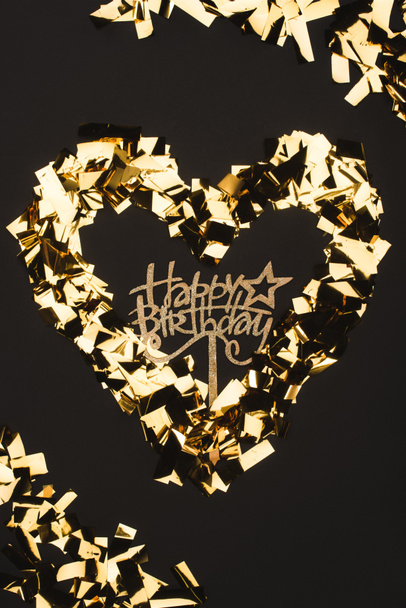 top view of happy birthday sign and golden confetti isolated on black - Foto, afbeelding