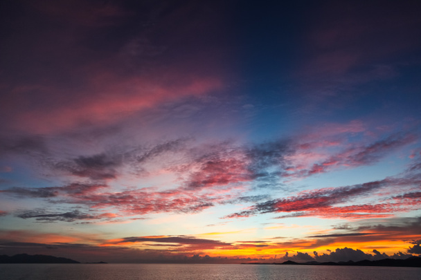 Farbenfroher Sonnenuntergangshimmel über ruhiger Meeresoberfläche - Foto, Bild