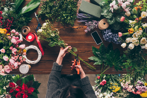 zugeschnittenes Bild eines Blumenhändlers, der Stiele von Rosen mit Baumschneider schneidet - Foto, Bild
